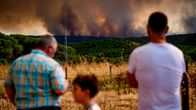 Ihmiset seuraavat Nieblan alueen maastopaloja Espanjassa, taustalla mustaa savua.