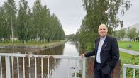 En man i kostym står på en bro.