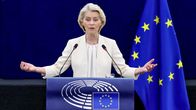 Nainen seisoo puhujakorokkeen takana mikrofonien edessä, taustalla EU:n lippuja ja Euroopan parlamentin logo.