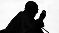 Paavi Franciscus kuvattuna varjossa, niin että hän näyttää varjokuvalta.