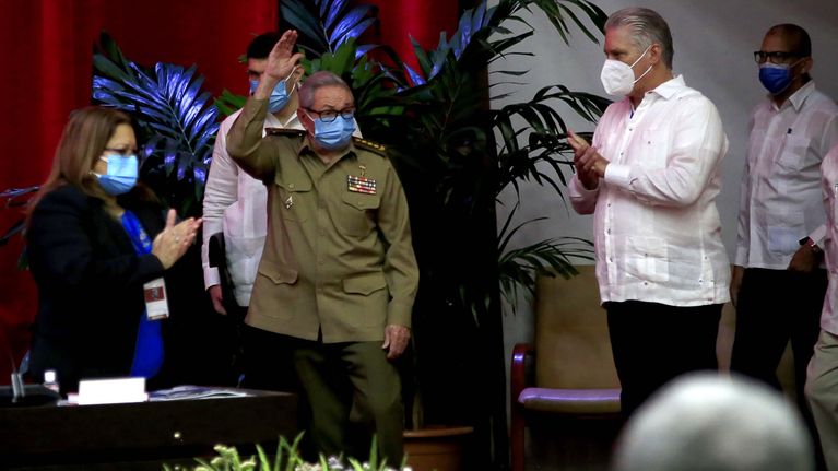 Miguel Diaz-Canel taputtaa, kun Raul Castro vilkuttaa yleisölle lavalla.