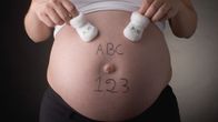En gravid mage med bokstäverna ABC och siffrorna 123 skrivna på magen. 
