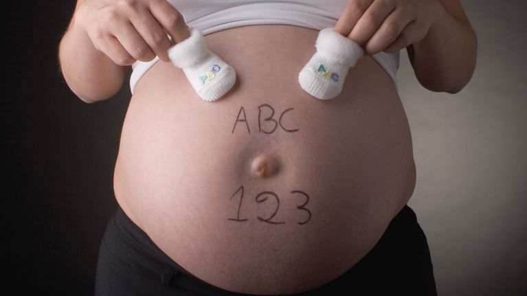 En gravid mage med bokstäverna ABC och siffrorna 123 skrivna på magen. 