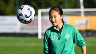 Fotbollsspelaren Queenie Xiang har blicken på bollen som är i ögonhöjd framför henne.
