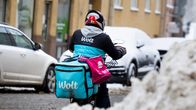 Polkupyörälähetti kuljettaa Woltin ja Foodoran ruokalähetyksiä kylmällä ilmalla. Hänellä mukana isot kuljetuslaukut molempien yritysten logoilla.