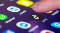 Lähikuva sormesta, joka painaa kosketusnäytöllä TikTok-mobiilisovelluksen pikakuvaketta.