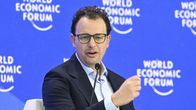 En man med mörkt hår och glasögon talar i en mikrofon. På väggen bakom honom står det World Economic Forum.