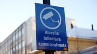 Blue sign with white lettering that reads "surveillance camera in use in the area" in Finnish.