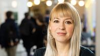 Kvinna med blont långt hår sitter med händerna i kors. 