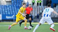 Elias Kallio med bollen. Han har gula spelkläder och möter en HJK-spelare i ljusa färger.