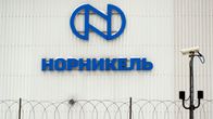 A photograph of a wall with the text Nornikel in blue Cyrillic letters. 