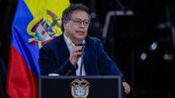 Gustavo Petro puhuu puhujakorokkeella mikrofoniin. Takana Kolumbian lippu.