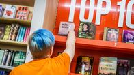 Myyjä laittaa kirjoja kirjakaupan top 10 -hyllyyn.
