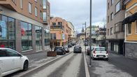 En bild av en gata i en stad med parkerade bilar och en kyrka i bakgrunden. 