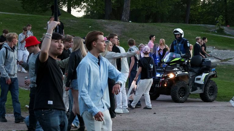 Poliisi mönkijän selässä ohjaa nuoria poistumaan puistosta.