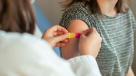 Ett barn får ett plåster på armen efter att ha fått en vaccination.