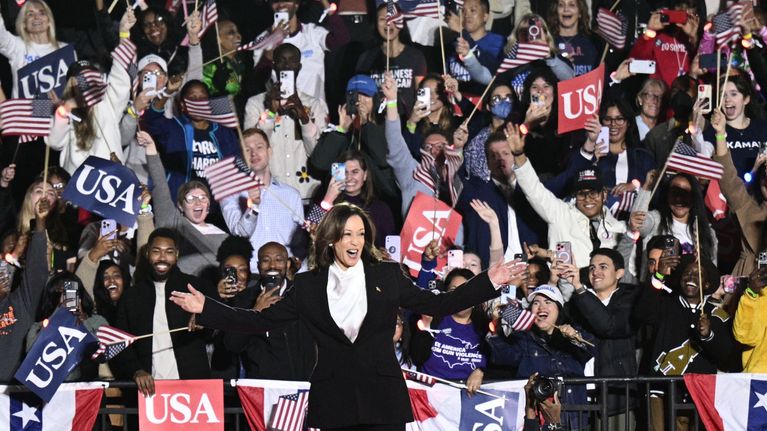 Kamala Harris med jublande, flaggviftande människor i bakgrunden. 