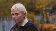 Michelle Haga seisoo syksyllä kerrostalon pihalla ja katsoo kameraan.