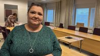 Nainen seisoo neuvotteluhuoneessa pukeutuneena vihreään kuvioituun mekkoon. Huoneessa on pitkät verhot ja suuria ikkunoita.