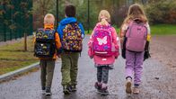 Fyra förstaklassister som går till skolan. Barnen är vända från kameran.