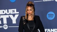 Tyra Banks poseeraa mainosseinän edessä.