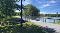Kevyen liikenteen silta, oikealla vettä ja vasemmalla vehreää puustoa. 