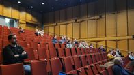 Personer sitter i ett auditorium och ser framåt. 