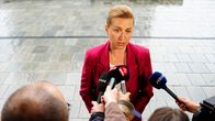 Mette Frederiksen framför en rad journalister med mikrofoner.