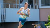Suunnistaja Tuomas Heikkilä juoksee rastilta nurmikolla piha-alueella.