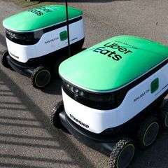 Two green and white delivery robots.