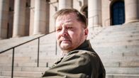 Vasemmistoliiton kansanedustaja Markus Mustajärvi istuu Eduskuntatalon edessä.