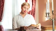 Anna Tulusto lukee Leo Tolstoin Anna Kareninaa aurinkoisen pöydän äärellä, edessä monihaarainen kynttelikkö