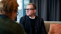 Petteri Orpo istuu tumma puku päällä, taustalla näkyy talvista maisemaa ikkunasta.