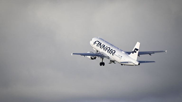 White passenger jet emblazoned with the word "Finnair" and the airline's logo, in blue. The plane is taking off into a grey sky.