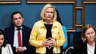 Woman in yellow denim jacket speaking at parliament.