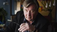 Aki Kaurismäki ottaa lasit pois päästään ja katsoo suoraan kohti kameraa.