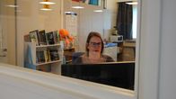 Kvinna sitter och jobbar vid dator i bibliotek.