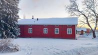 Punainen puutalo on talvisessa maisemassa. 