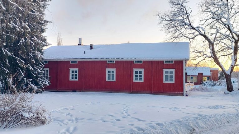 Punainen puutalo on talvisessa maisemassa. 