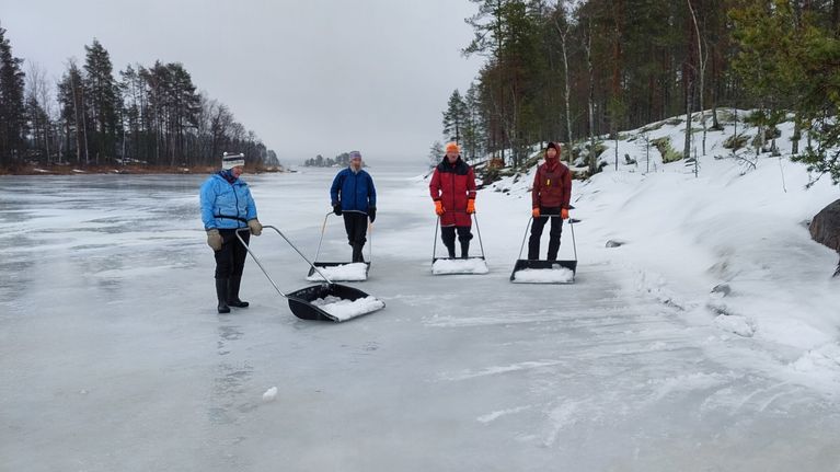 Ihmisiä kolaamassa lunta jäällä norppien apukinoksiin.