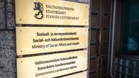 Valtioneuvoston, sosiaali- ja terveysministeriön ja valtiovarainministeriön kyltit talon seinässä.