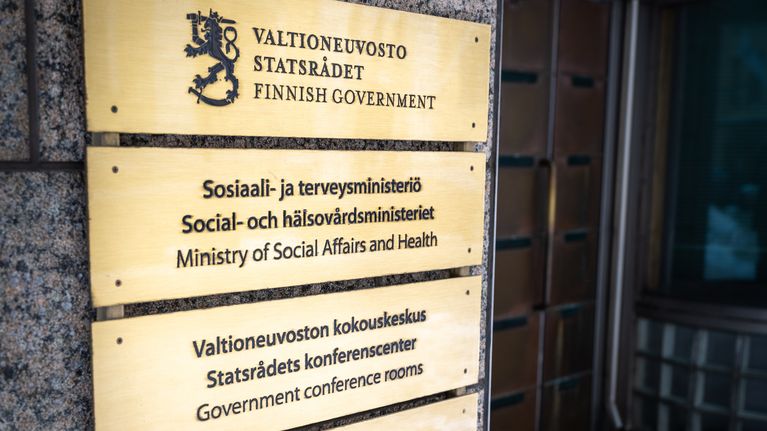 Valtioneuvoston, sosiaali- ja terveysministeriön ja valtiovarainministeriön kyltit talon seinässä.