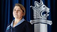 Siniseen univormuun pukeutunut Sanna Heikinheimo poseeraa poliisin miekka-symbolin vieressä.