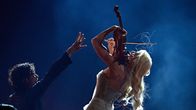 A man and a woman on stage performing. She is playing the violin, he is gesturing with his hand.