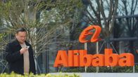 Puhelintaan selaava mies kävelee oranssin Alibaba-logon ohi.