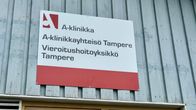 A red-and-white sign for an A-Clinic detox centre in Tampere, attached to a light-blue wooden wall.
