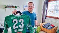 En person håller upp en grön tröja med nummer 23 och namnet "Melwin" på ryggen.