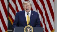 Trump seisoo puhujakorokkeen takana ja puhuu mikrofonin kautta, taustalla Yhdysvaltain lippuja.