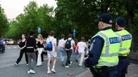 Kaksi poliisia katsoo jalkakäytävällä käveleviä nuoria puiston läheisyydessä.
