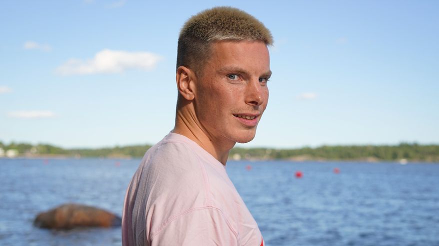 Lähikuvassa mies seisoo rannalla kääntyneenä katsomaan kameraan.